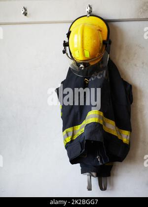 Firefighter, uniform and clothing hanging on wall rack at station for ...