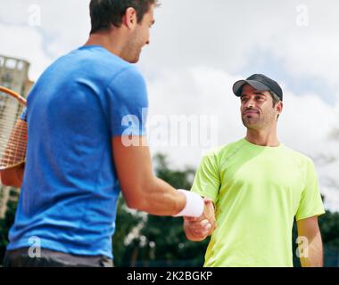Good game. Shot of two tennis players shaking hands. Stock Photo