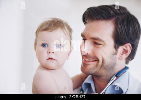 Shes such a healthy little girl. Closeup shot of a young male doctor holding an infant girl in his arms. Stock Photo