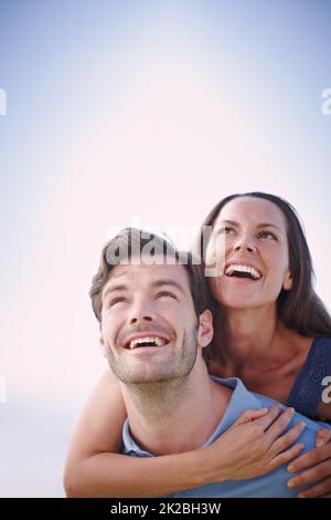 Joyous time together. A handsome man piggybacking his loving wife outdoors. Stock Photo