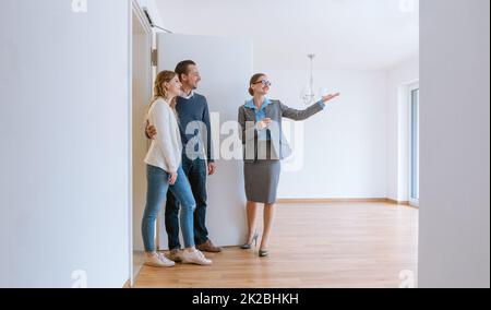 Realtor showing house to a young couple Stock Photo