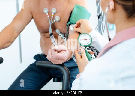 Doctor woman measuring blood pressure during ecg Stock Photo
