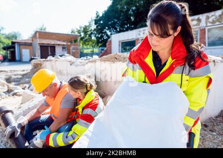 Emergency doctors giving first aid to construction worker Stock Photo