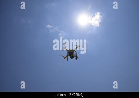 Drone DJI Phantom 4 in flight. Quadrocopter against the blue sky with white clouds. The flight of the copter in the sky. Stock Photo