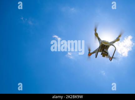 Drone DJI Phantom 4 in flight. Quadrocopter against the blue sky Stock Photo