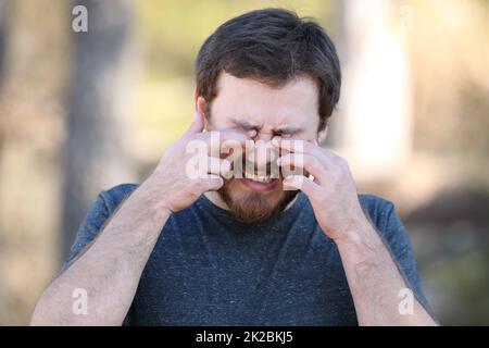 Man scretching itchy eyes in nature Stock Photo