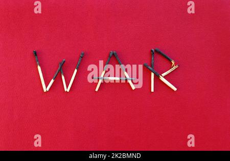 Burnt matches forming the word WAR on a red paper background Stock Photo