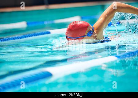 Working on her stroke. Shot of a professional female swimmer freestyle swimming in her lane. Stock Photo