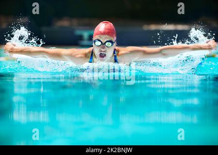 The hardest stroke in swimming.... Shot of a young female swimmer doing the butterfly stroke. Stock Photo