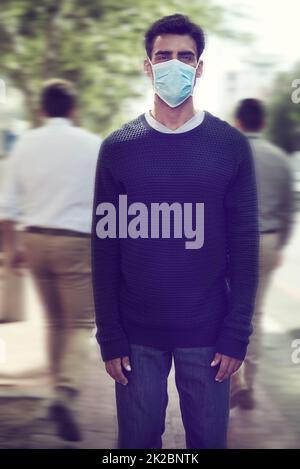 Flu season is here. Shot of a man wearing a surgical mask in a crowd. Stock Photo