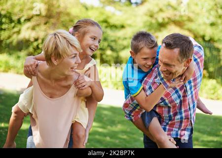 Whos going to win. Two parents having a race while carrying their young children on their backs. Stock Photo