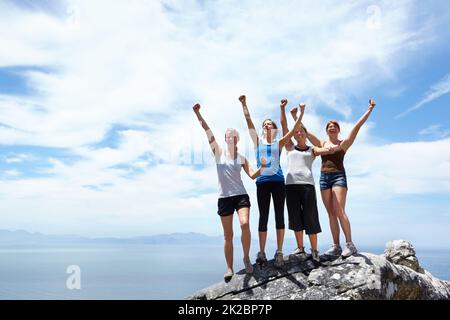 Getting to the top. Shot of a group of friends looking pleased after reaching the peak of a mountain. Stock Photo