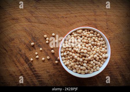Uncooked chickpeas in bowl on wooden background. top view Stock Photo