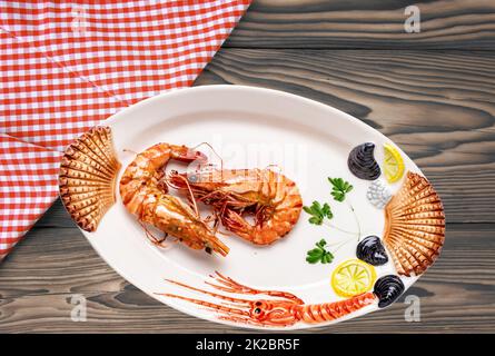 Closeup of fresh grilled large tiger prawns or shrimps on a colourful plate of seafood on rustic table with plaid cloth. Healthy food concept. BBQ. Seafood background. Space advertising. Stock Photo