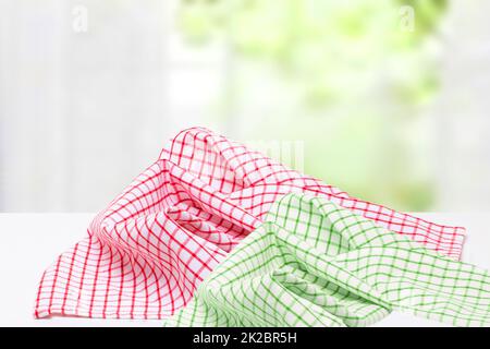 Empty desk table with red and green checkered tablecloth over abstract bright light green yellow spring or summer background. Template for your food and product display montage. Stock Photo