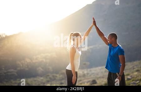 If you cant excel with talent, triumph with effort. Shot of a sporty couple high-fiving after a run. Stock Photo