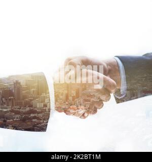 Making deals in the city. Multiple exposure shot of two businessmen shaking hands together superimposed over a cityscape. Stock Photo