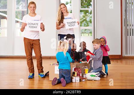 Giving back to the community. Shot of volunteers working with little children. Stock Photo