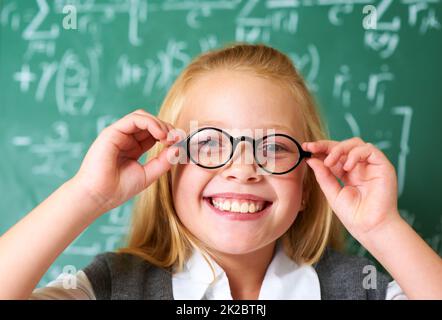 Let me put my glasses on first. Portrait of a cute blonde girl adjusting her glasses in class. Stock Photo
