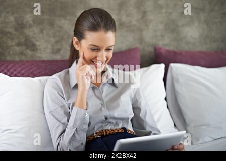 Relaxation after a long work day. Shot of a young businesswoman using a tablet while sitting in a bed. Stock Photo