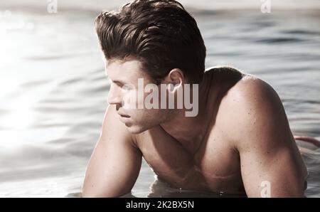 Taking in the view. A contemplative male model lying in water. Stock Photo