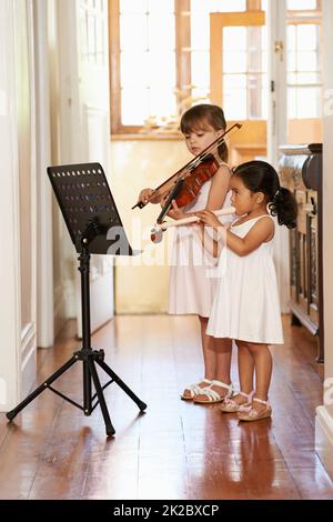 Playing a violin duet. Full-length shot of two little girls playing violins. Stock Photo