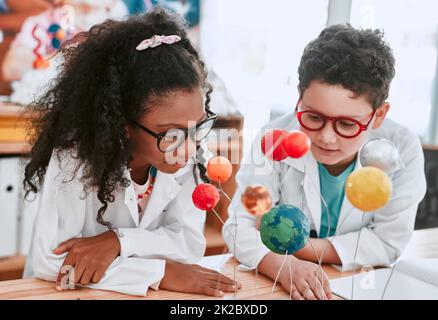 The solar system is so vast and interesting. Shot of two adorable young school pupils learning about planets and the solar system in science class at school. Stock Photo