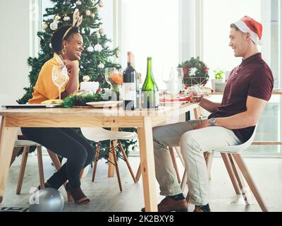 By the way you did such a great job decorating. Full length shot of a cheerful young couple having a chat during Christmas lunch at home. Stock Photo