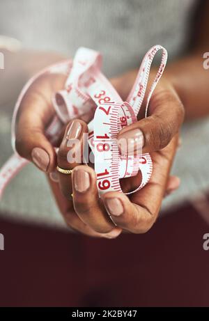 Made to measure. Cropped shot of an unrecognizable fashion designer holding measuring tape. Stock Photo
