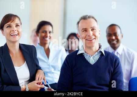 Executives smiling while listening presentation. Group of executives listening to presentation. Stock Photo