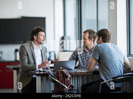 Getting his ideas across. three businessman discussing work in the office. Stock Photo