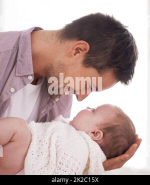 Daddys little angel. Side view of a young father holding and looking at his adorable baby girl. Stock Photo