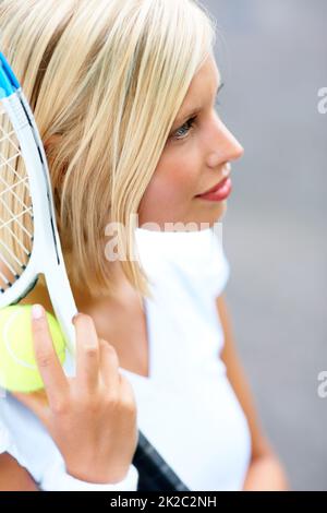 Feeling fully focused on winning. A young female tennis player with her racquet and ball in her hand. Stock Photo