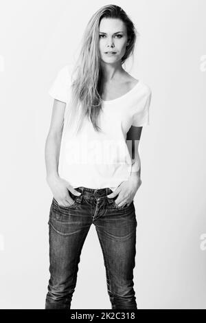Monochrome chic. Croppy studio portrait of a an attractive young woman standing with her hands in her pockets.