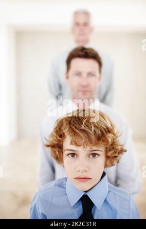 Hes the latest addition to his multi-generational family. Cropped portrait of a young boy standing with his father and grandfather. Stock Photo