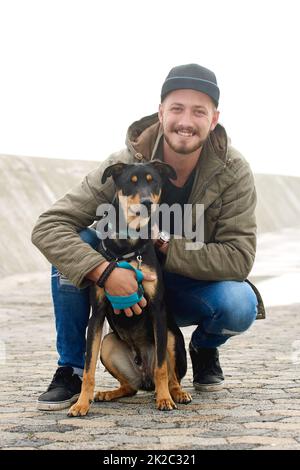 He really is mans best friend. Portrait of a young man and his dog spending time together outdoors. Stock Photo