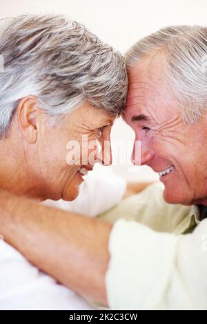Smiling mature couple looking at each other. Closeup of affectionate mature couple smiling while looking at each other, head to head. Stock Photo