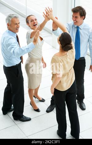 Group of happy business people celebrating success. Group of joyful business people together celebrating their success with a high five. Stock Photo