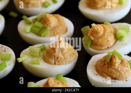 Deviled eggs with cod livers with leek on on black background Stock Photo