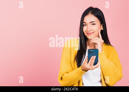 woman excited smiling holding mobile phone and think idea Stock Photo