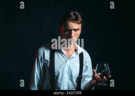 Elegant and stylish man in classical wear with wiskey. Stylish rich young man holding a glass of old whisky. Stock Photo