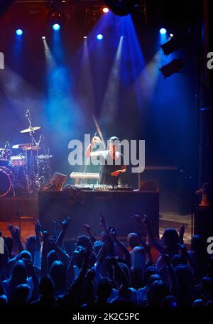 A DJ playing his live set to a group of screaming fans. This concert was created for the sole purpose of this photo shoot, featuring 300 models and 3 live bands. All people in this shoot are model released. Stock Photo