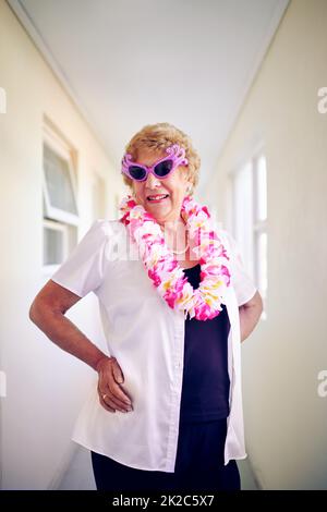 I feel young again. Shot of a carefree elderly woman wearing pink glasses and posing inside of a building. Stock Photo