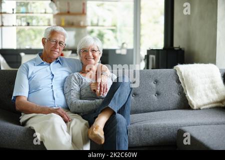 Love is just a word until someone gives it meaning. Portrait of a happy senior couple sitting in their living room. Stock Photo