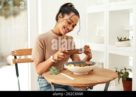 This looks so delicious. Cropped shot of an attractive young businesswoman using her cellphone to take pictures of her lunch for her blog. Stock Photo