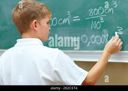 Hes a junior genius. Young schoolboy doing an equation on the blackboard at school. Stock Photo