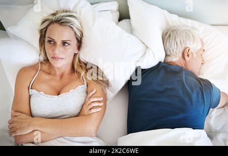I cant just sleep our problems away like he does. Shot of a mature couple having marital problems at home. Stock Photo