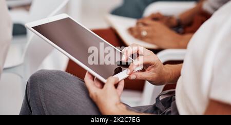 Are you keeping up with the technological evolution. Closeup shot of an unrecognisable businesswoman using a digital tablet in an office. Stock Photo