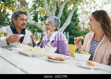 Dads jokes have them rolling in the aisles. Cropped shot of a family enjoying lunch and wine together outside. Stock Photo