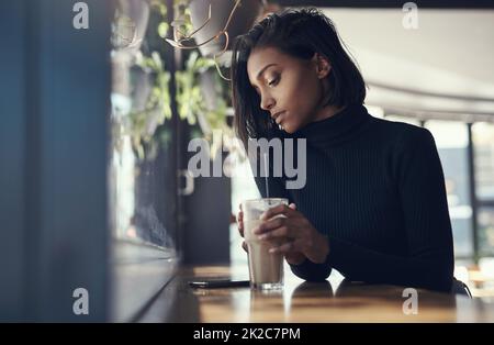 Never keep a good woman waiting. Shot of a beautiful young woman drinking a iced coffee in a cafe. Stock Photo